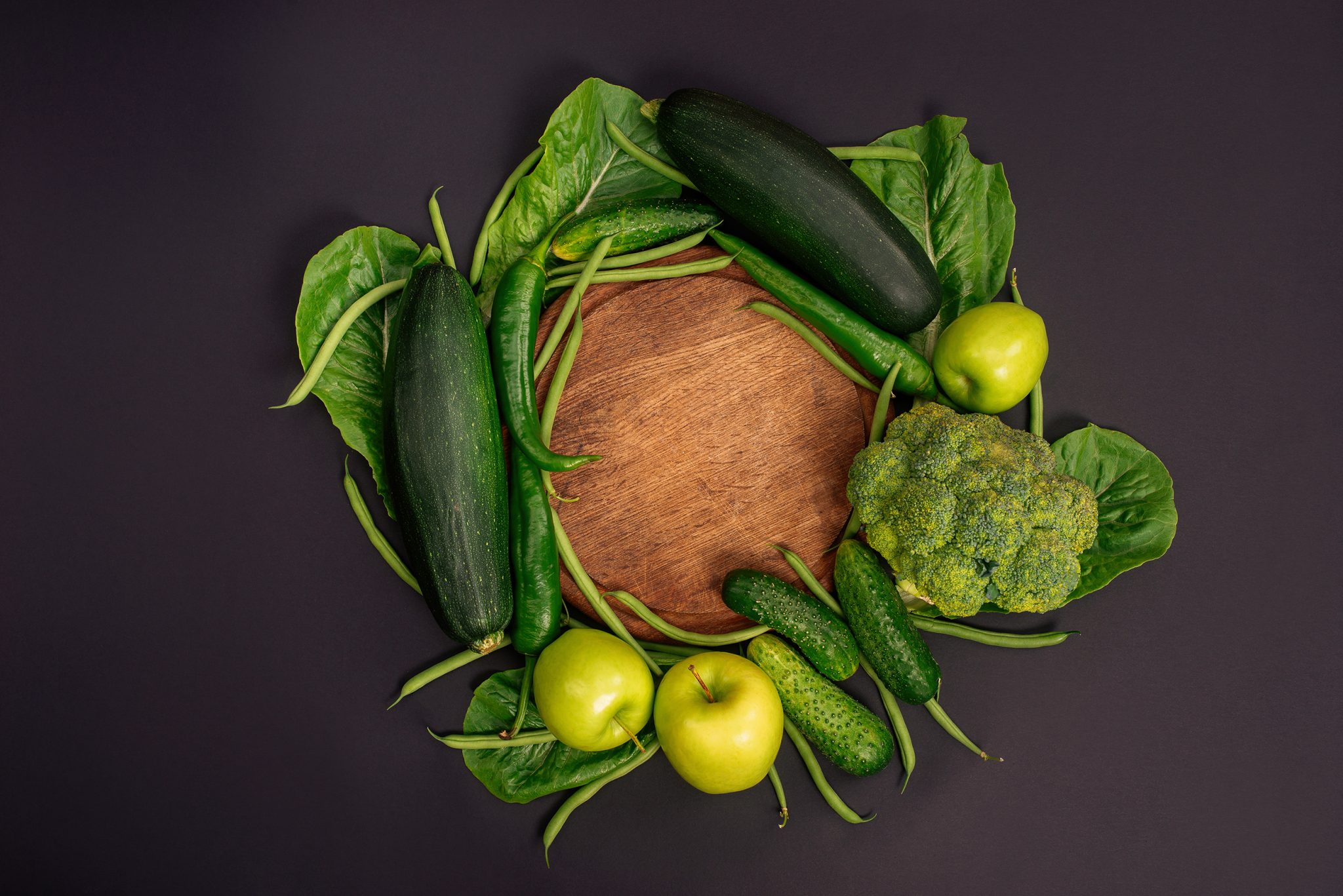 green vegetables on a black background with a board